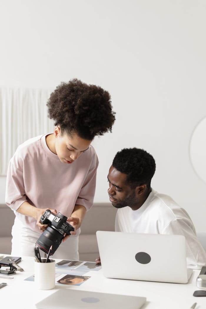 Photographers collaborate on project, reviewing shots on DSLR camera in a studio setting.